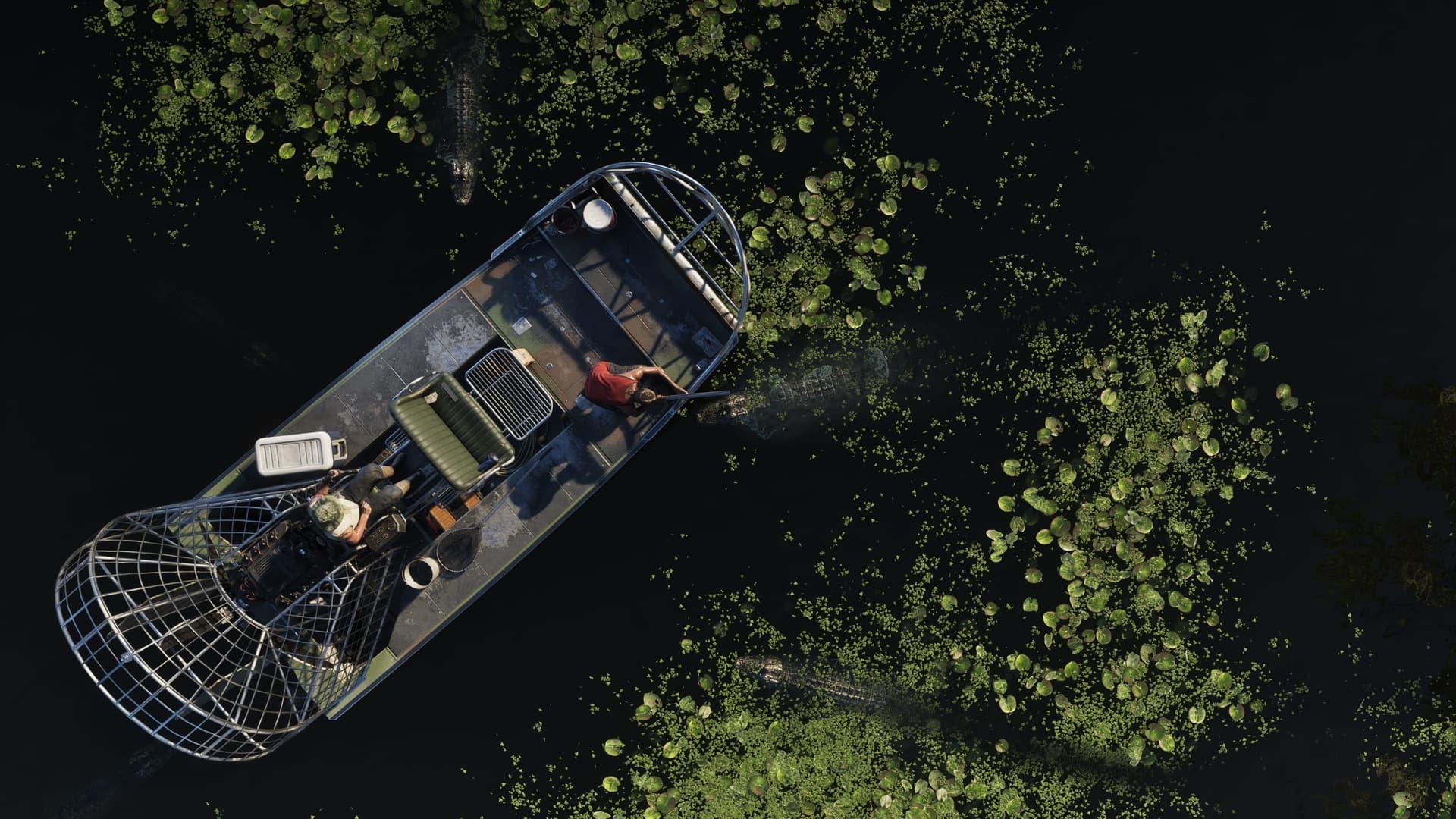 A top-down view of an airboat with a cage-like bow and two people aboard, over dark water and lily pads