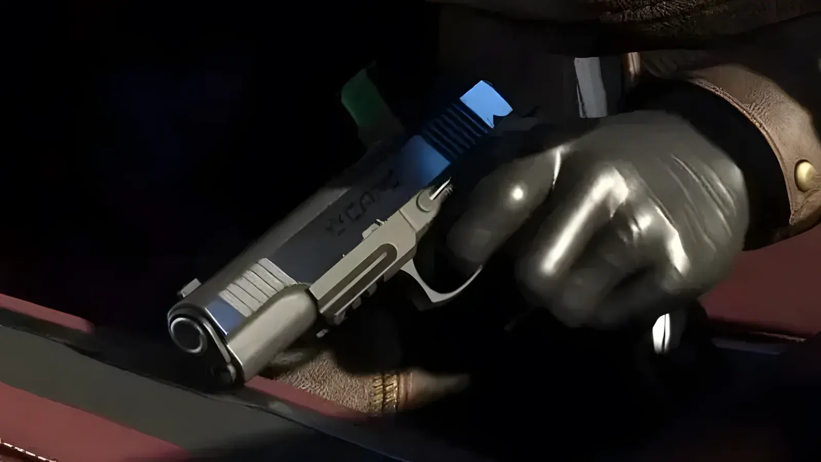Heavy Pistol in GTA 6, basata sull’arma reale M1911 Variant. Primo piano di una mano guantata che regge una pistola semiautomatica argentata in penombra, screenshot ufficiale di GTA 6