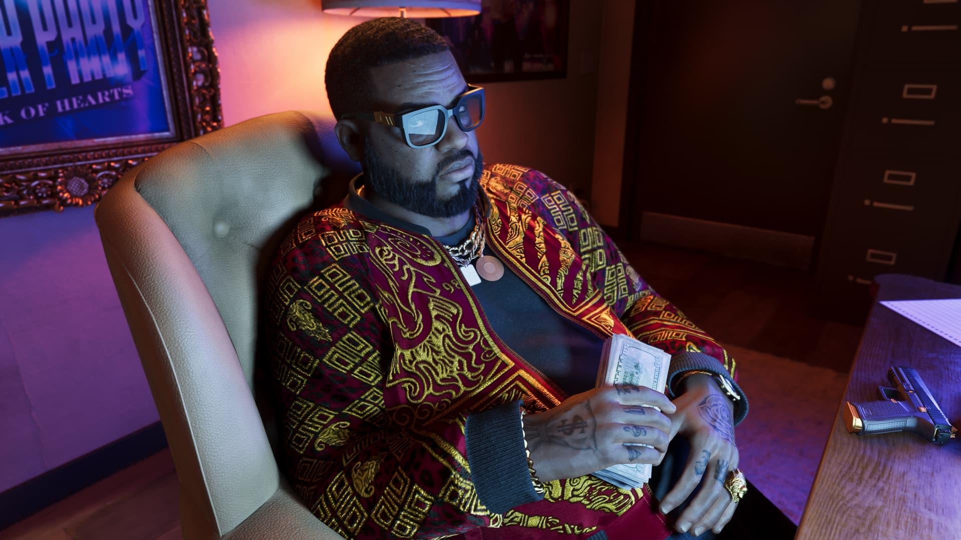 GTA 6 official screenshot of a character seated in an office chair holding a stack of cash, with a pistol resting on the desk