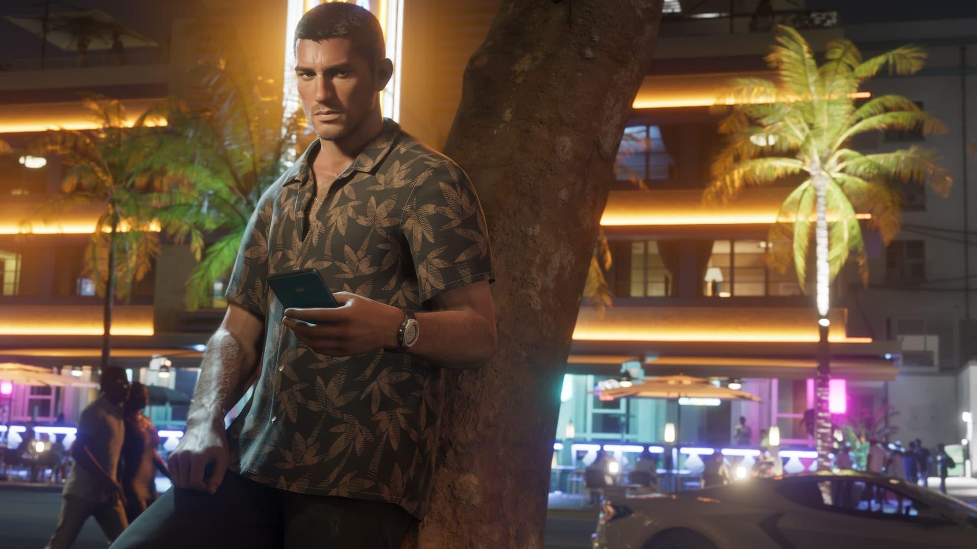 Jason Duval lehnt nachts an einer Palme, ein Handy in der Hand, hinter ihm neonbeleuchtete Gebäude, in einem offiziellen GTA-6-Screenshot