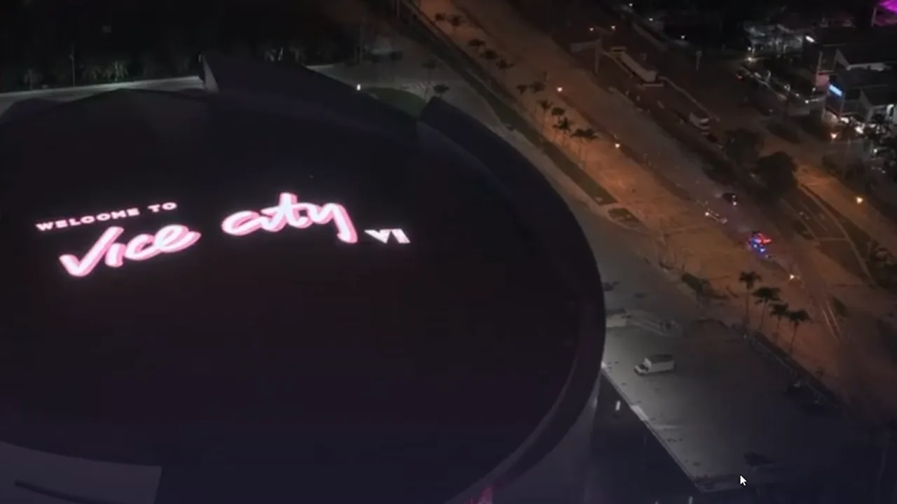 Aerial night view of the Kaseya Center roof lit with the words Welcome to Vice City VI in pink script above a lit street for the GTA 6 collab