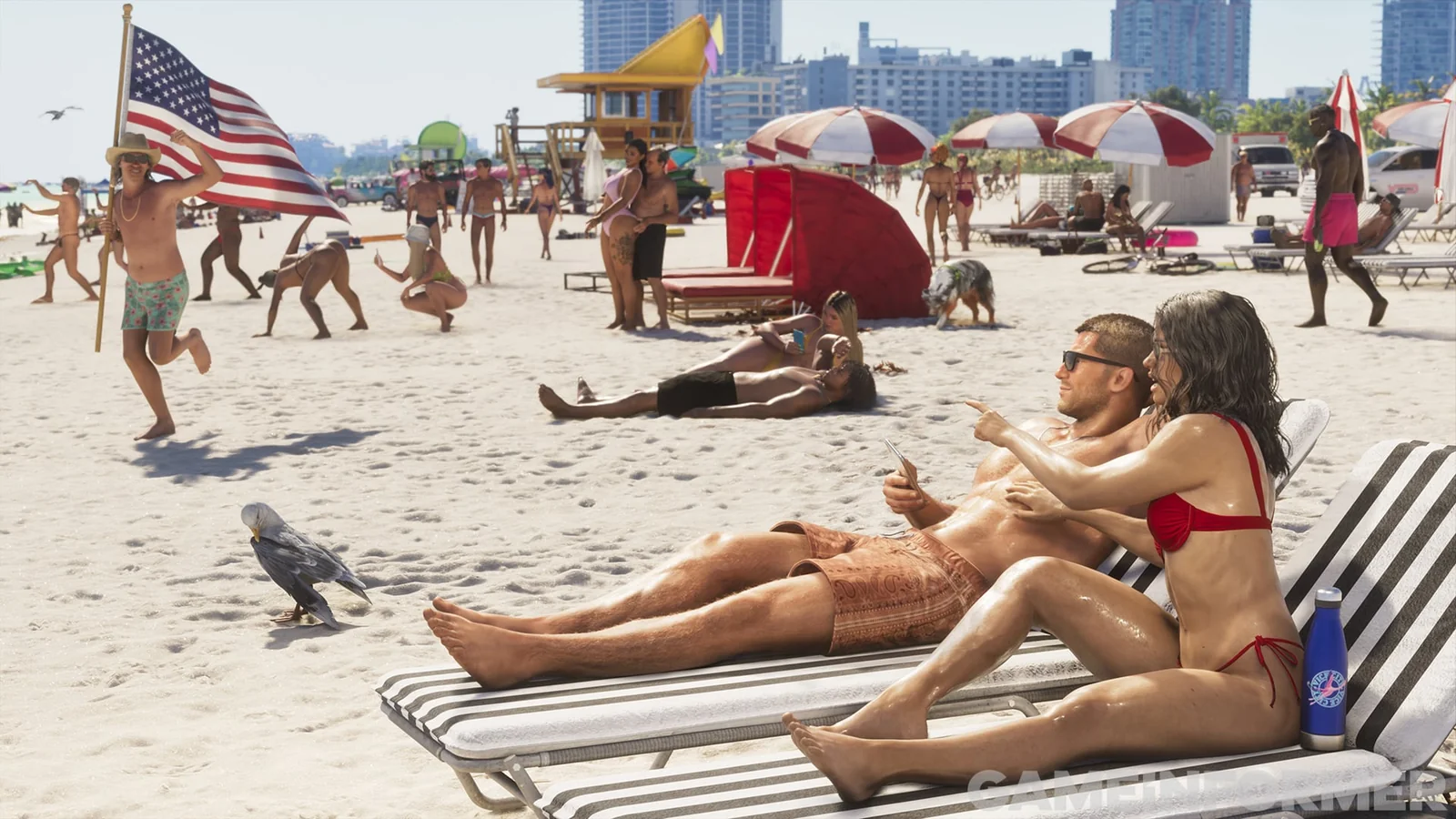 Couple on striped loungers on a crowded beach, the man holding a phone, with a man running behind them carrying a US flag in GTA 6
