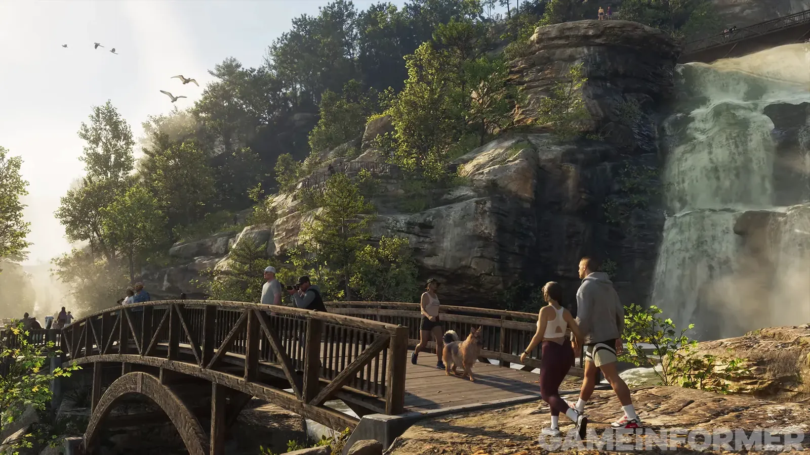 Couple walking past a wooden footbridge and waterfall while a woman walks a dog across and a man photographs the falls in GTA 6