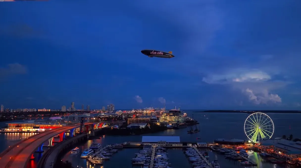 GTA 6 Vice City blimp flying over the Miami waterfront at dusk with a lit Ferris wheel and a highway bridge, in a clip TGG shows