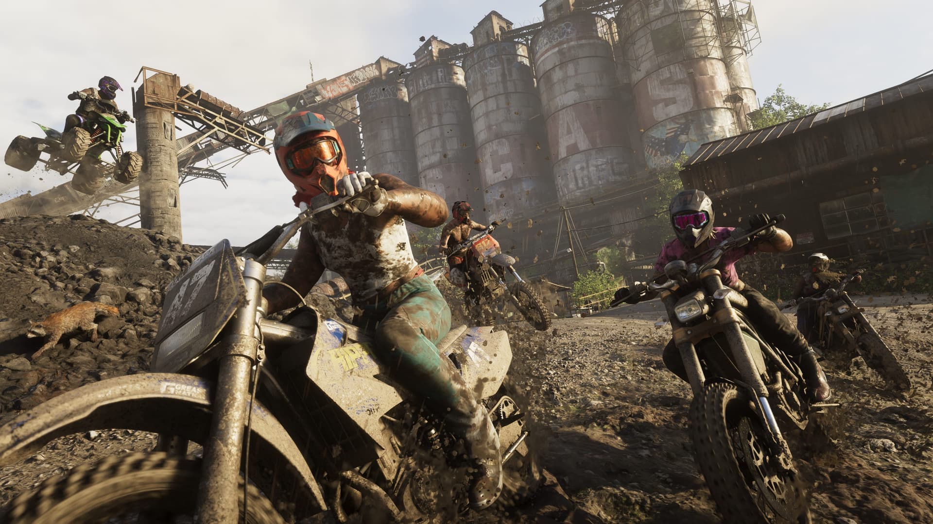 Riders on dirt bikes and a quad kicking up mud in front of concrete silos in a GTA 6 Mount Kalaga National Park screenshot
